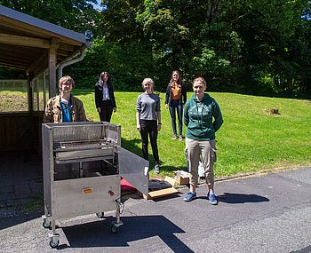 Menschen stehen neben einem Grill