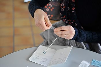 Eine Person beim Öffnen einer Flüssigkeitsflasche mit dem Covid-Testkit