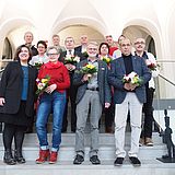 Menschen mit Blumen stehen auf einer Treppe