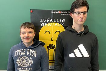 Zwei Personen stehen vor einem "Jugend forscht"-Plakat