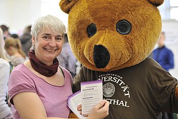 Person steht neben jemandem, der ein Bärenkostüm